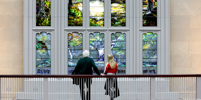 Photo of an older man and younger woman looking at a stained glass window